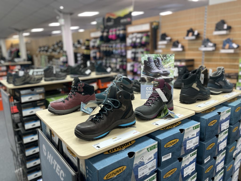 a display of hiking shoes and boots in the walking and hiking section of a camping shop.